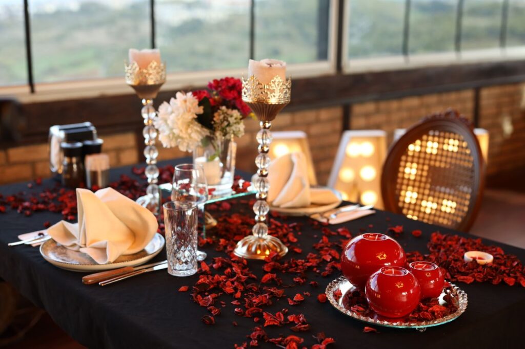 Elegant table setting with red accents and candles, perfect for a romantic dinner or intimate celebration.