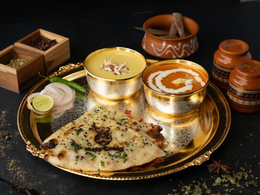 A delectable Indian thali featuring dal, butter chicken, and naan on a golden platter.